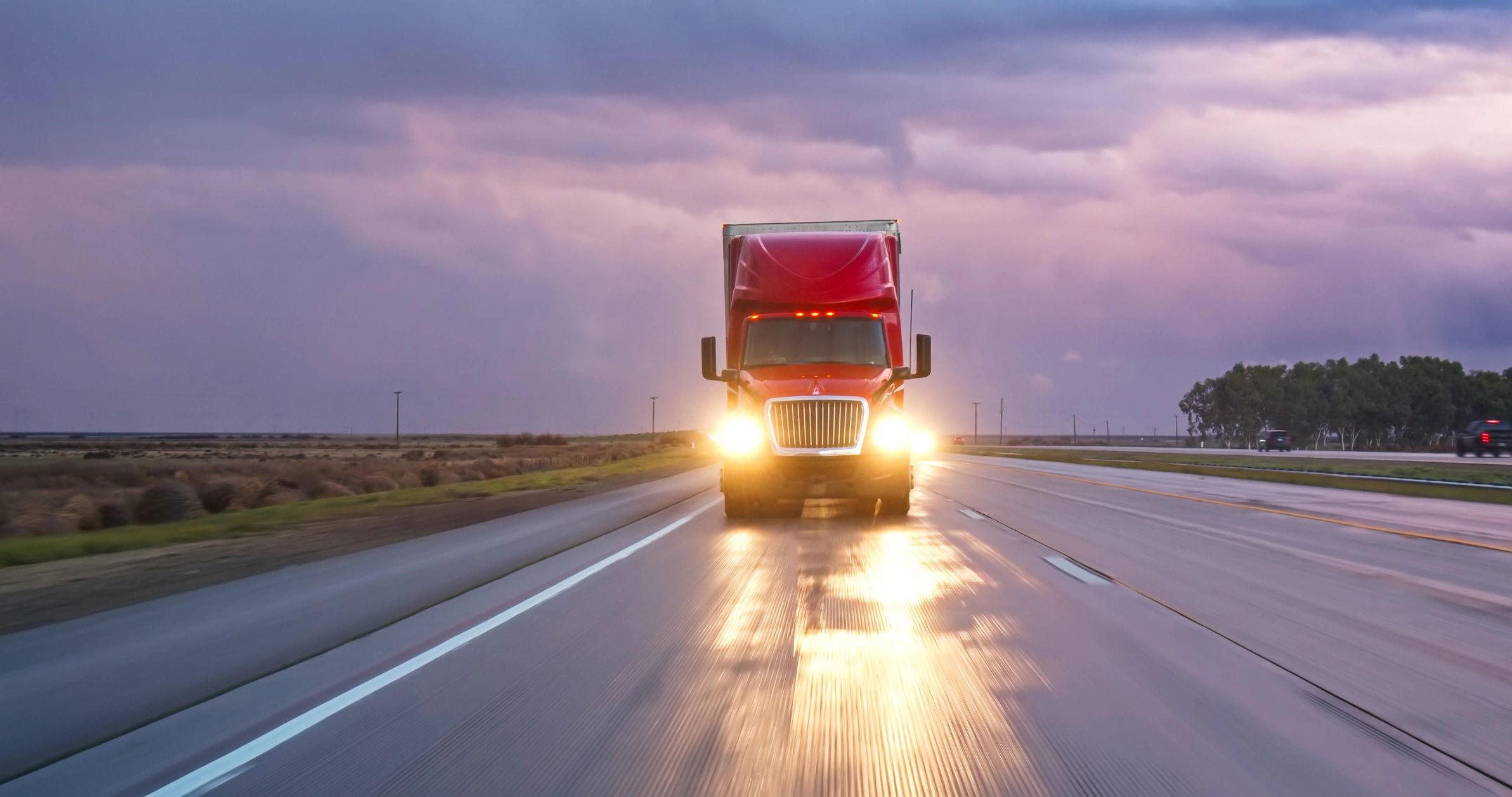 Cargo truck driving on a motorway at sunset